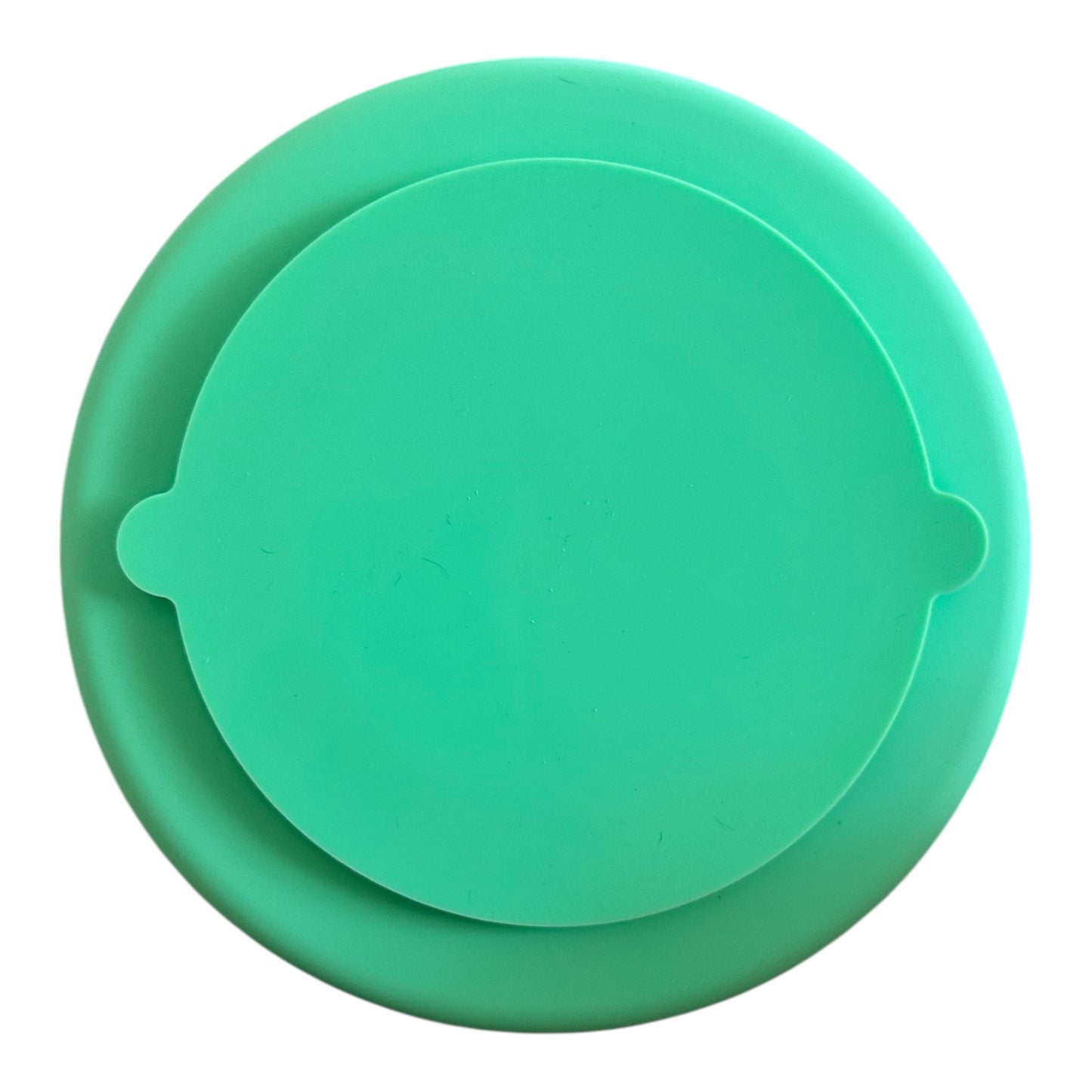 The bottom of a green silicone slow feeder bowl on a white background