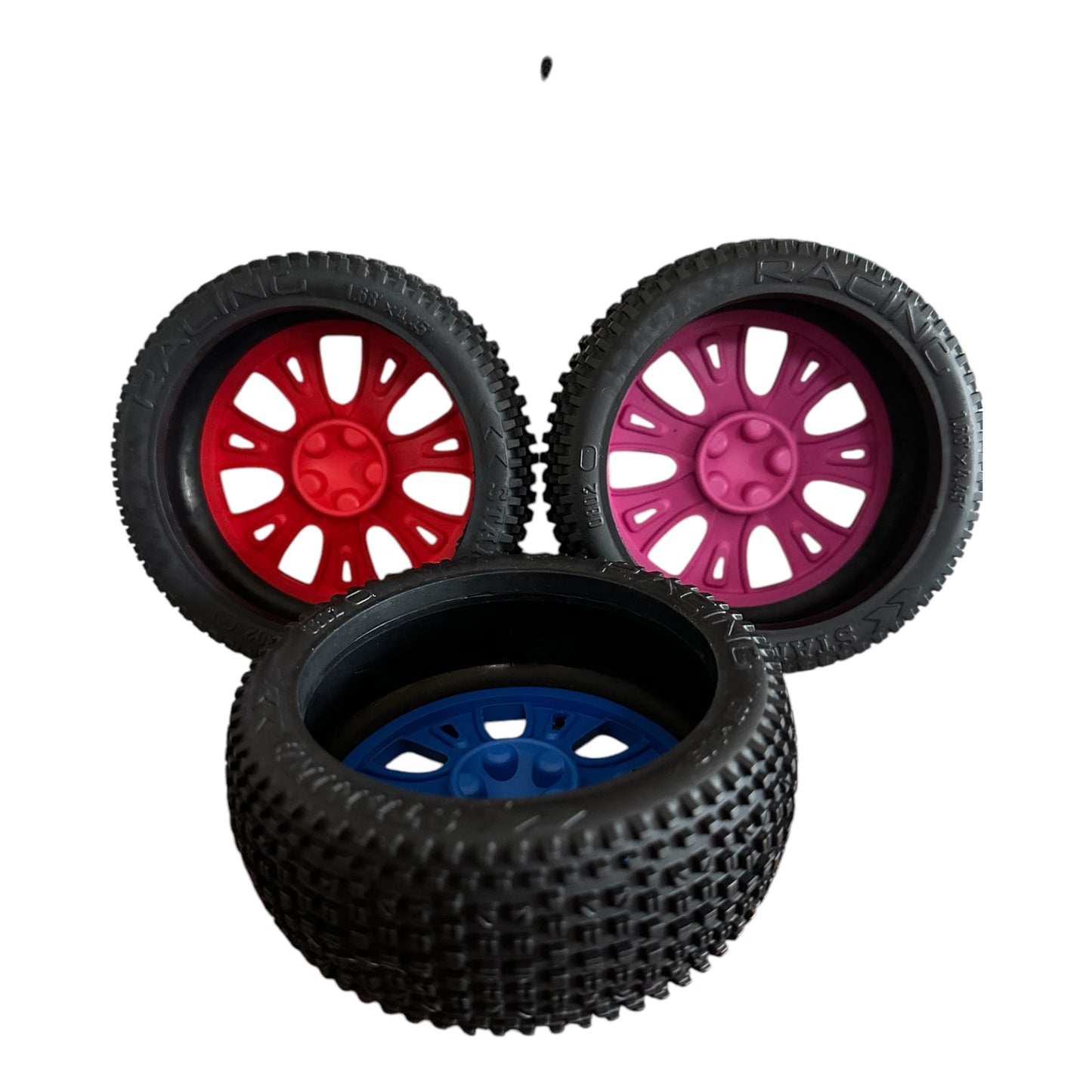 Three natural rubber dog toys in the shape  car tyres, viewed from behind, in red pink and blue.